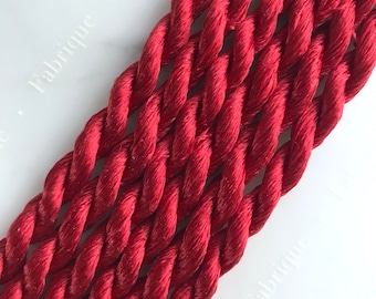 May include: Close-up of a red twisted cord, showing the texture and detail of the braided rope.