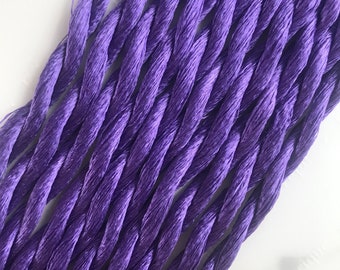 May include: A bundle of purple embroidery floss, a type of thread used for hand sewing and embroidery.