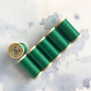 May include: Five spools of green thread, each with a label that reads "Fil A Gan 868" and a barcode. The spools are arranged in a row, with the label facing up.