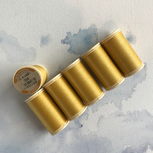 May include: Six spools of gold thread, each with a white label that reads "Fil a Gant 334" and a barcode.