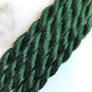 May include: Close-up of a deep green twisted cord made of multiple strands of thread.