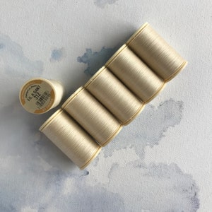 May include: Six spools of off-white thread, each with a label that reads "Fil a Gant 312 1 100% Cotton 40m/131yd Made in France".