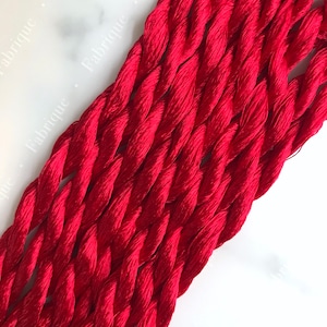May include: A bundle of red embroidery floss, a type of thread used for hand embroidery.