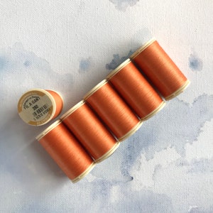 May include: Six spools of orange thread, each with a white label that reads "Fil a Gant 390 1 16791 913896 AU CHINOIS".
