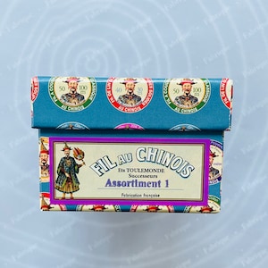 May include: A blue box with a purple label that reads "Fil au Chinois Ets Toulemonde Successeurs Assortiment 1 Fabrication française". The box is decorated with images of Chinese men in traditional clothing and the text "Fil au Chinois" repeated multiple times.