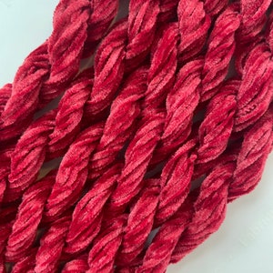 May include: Close-up of a bundle of red velvet cord. The cord is twisted and has a soft, fuzzy texture.