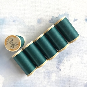 Puede incluir: Seis carretes de hilo verde oscuro, cada uno con una etiqueta que dice "Fil a Gant 879" y "Au Chinois".