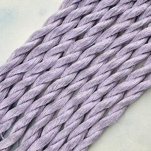 May include: A bundle of lavender-colored embroidery floss, arranged in a diagonal pattern. The floss is made of a soft, silky material and is perfect for hand embroidery projects.