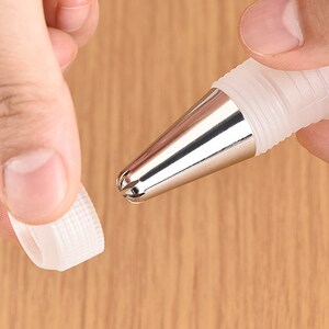 May include: A silver and white piping tip with a star-shaped opening. The tip is attached to a clear plastic coupler.