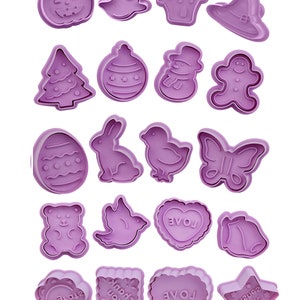 May include: Set of 18 purple plastic cookie cutters featuring various holiday and everyday themes, including a pumpkin, ghost, house, witch hat, Christmas tree, ornament, snowman, gingerbread man, Easter egg, bunny, chick, butterfly, bear, bird, heart, bell, square with "Thank You" text, heart with "LOVE" text, and a star with "Mini Bear" text.