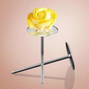 May include: Two silver cake decorating tools with round bases and long, thin, pointed stems. One tool has a yellow buttercream rose on top of the base.