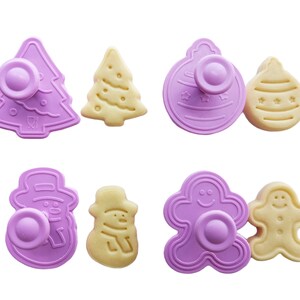 May include: Set of eight purple plastic cookie cutters in the shapes of a Christmas tree, a snowman, a gingerbread man, and a Christmas ornament. The cutters are paired with matching cookies.