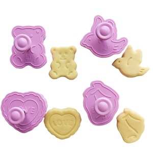 May include: Set of eight pink plastic cookie cutters in various shapes, including a bear, a bird, a heart, and a house. The cutters are shown with matching cookies.