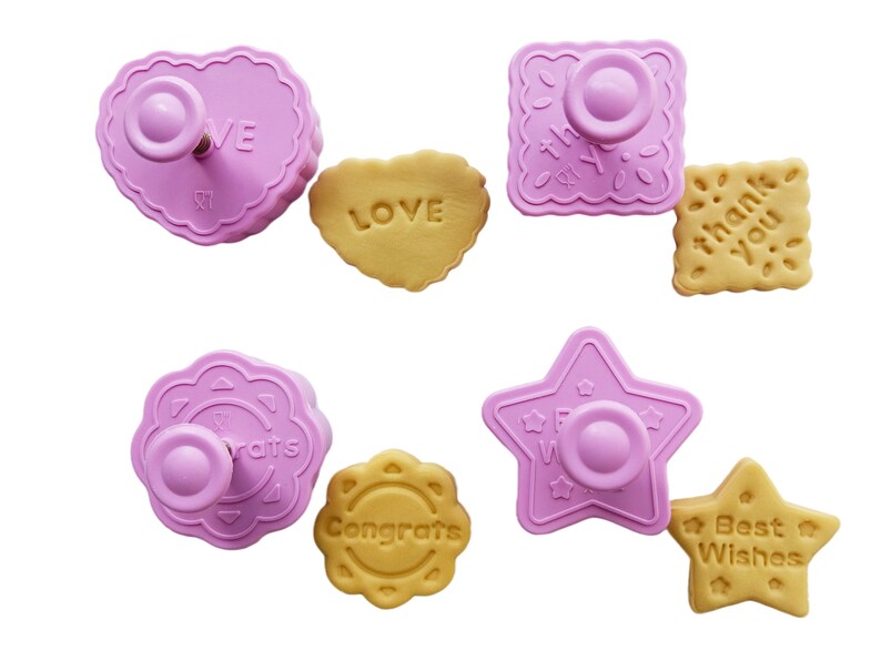May include: Set of six pink plastic cookie cutters with different shapes and designs. The cutters are used to create cookies with the words "Love", "Congrats", "Best Wishes", "Thank You", "Congrats" and "Star".