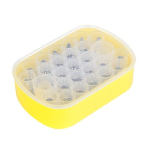 May include: A yellow plastic container with a clear lid filled with 30 different metal piping tips for decorating cakes and pastries.