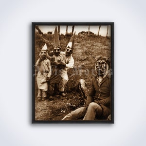 May include: A vintage black and white photograph of four people wearing masks. Three people are standing in a group, while one person is sitting down. The people are wearing masks that appear to be made of paper or cardboard. The masks are all different and have various expressions. The photograph is taken outdoors in a field.