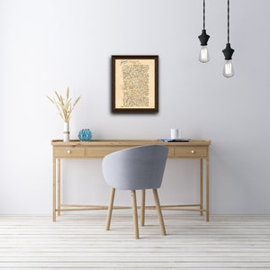 May include: A framed document with handwritten text in blue ink. The document is titled "Declaration of Independence" and is displayed on a white wall above a wooden desk with a chair.