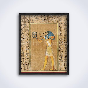 May include: Framed print of an ancient Egyptian illustration. The artwork depicts a figure with a bird head, wearing a blue and gold headdress, holding an object. The background is tan with hieroglyphs and a black frame.