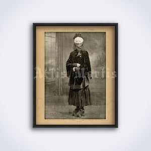 Pode incluir: Uma fotografia vintage em preto e branco de uma pessoa vestindo um longo vestido preto e um chapéu, em pé em patins. O rosto da pessoa está coberto por uma máscara branca.