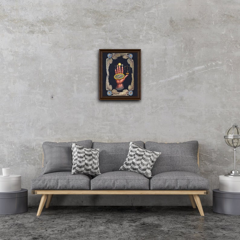 May include: A framed artwork depicting a hand holding a celestial sphere with planets and stars. The hand is surrounded by a decorative frame with wings and celestial symbols. The background is a dark blue.