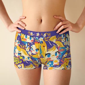 May include: Boxer shorts in blue, yellow, and white, featuring a repeating cartoon character and floral design. The waistband is solid blue with a floral pattern. The text "Free Funky" is visible on the shorts.