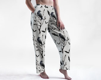 May include: White pants with a black crow and bat print. The pants have a wide leg and a relaxed fit.
