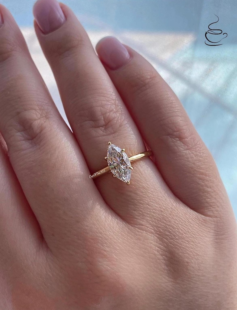 K&ouml;nnte beinhalten: Ein goldener Ring mit einem gro&szlig;en, klaren, markisenf&ouml;rmigen Diamanten.