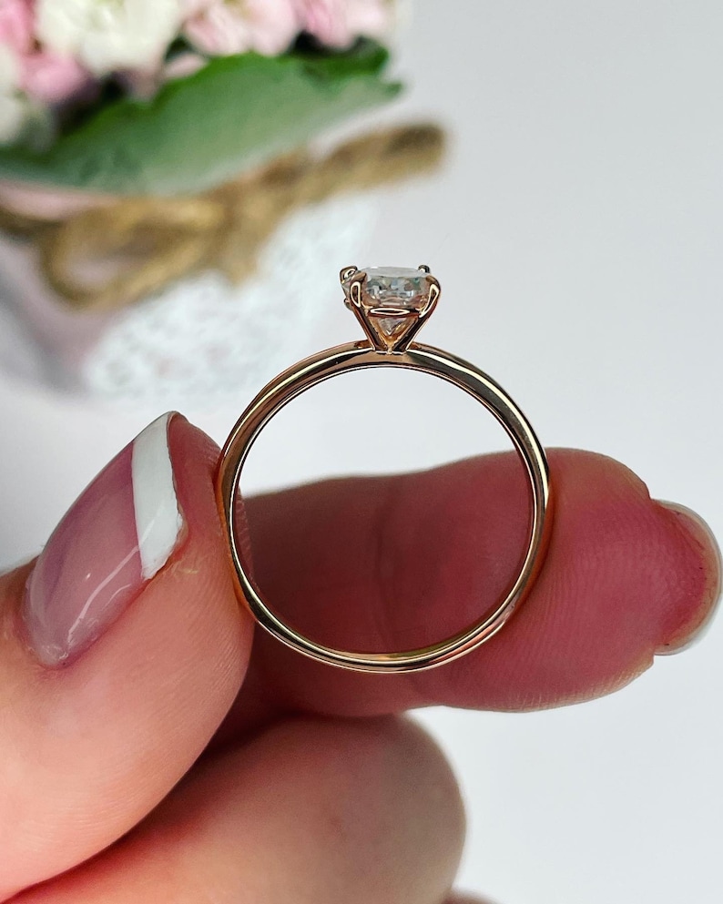 Puede incluir: Un anillo de compromiso de oro rosa con un solo diamante redondo.