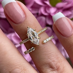 Könnte beinhalten: Ein goldener Ring mit einem großen birnenförmigen Diamanten und kleineren Diamanten, die in einer Band eingefasst sind, die sich um den Finger wickelt.