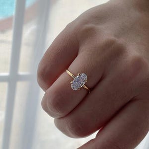 Puede incluir: Un anillo de oro con una gran piedra preciosa ovalada transparente.