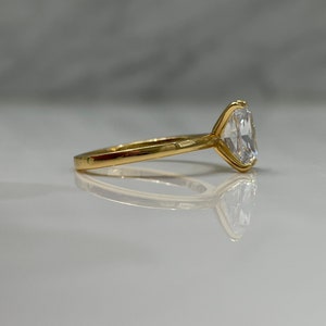 May include: A gold ring with a large, clear, oval-shaped gemstone.
