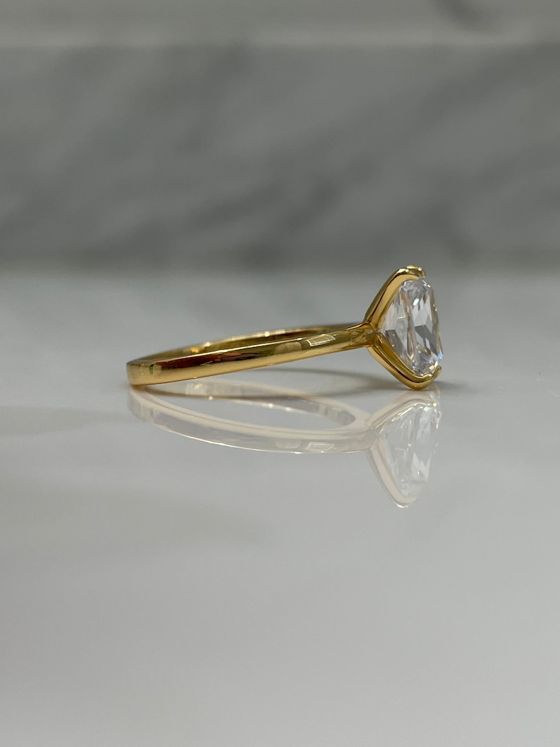 May include: A gold ring with a large, clear, oval-shaped gemstone.