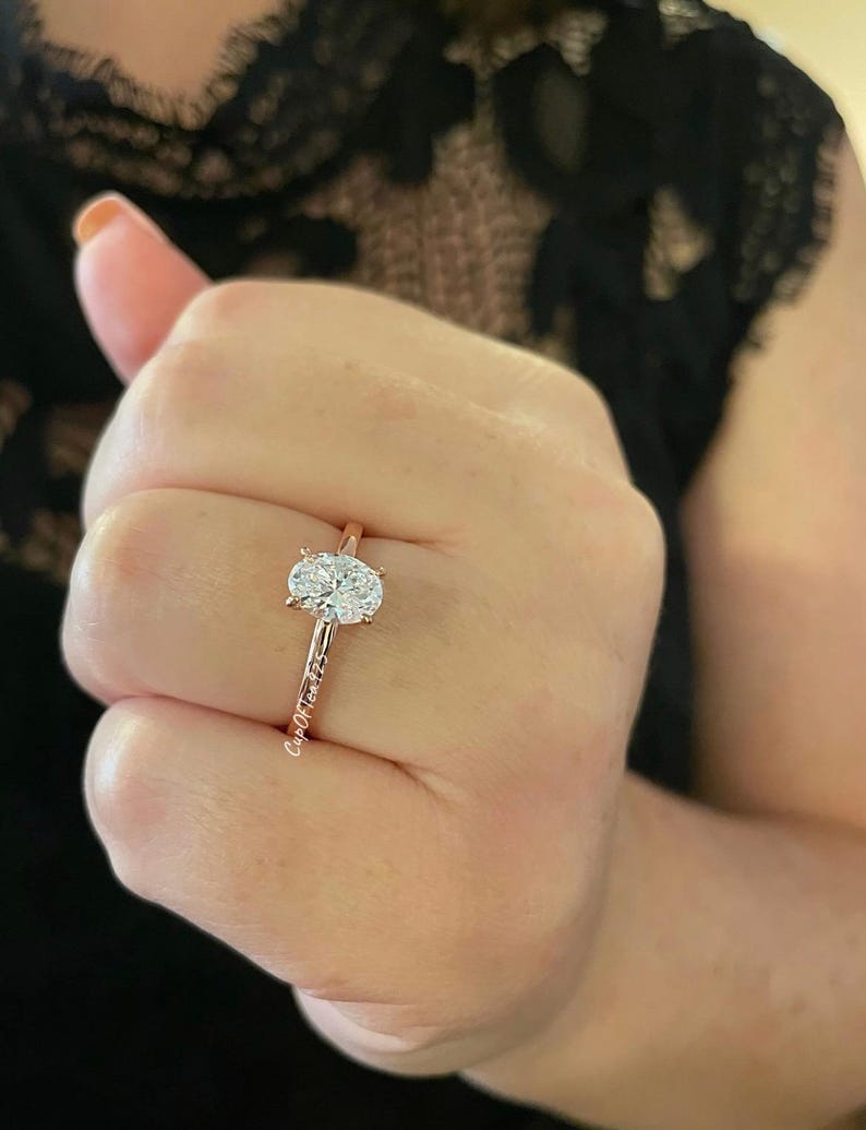 Puede incluir: Un anillo de compromiso de oro rosa con un diamante de forma ovalada.
