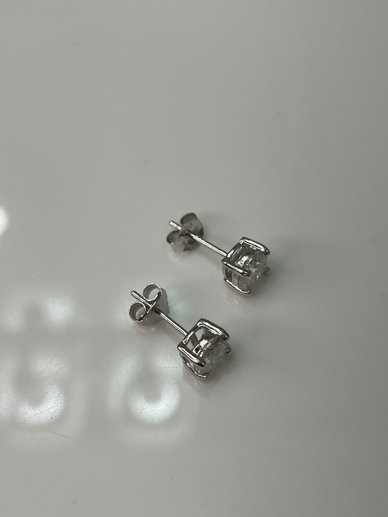 May include: A pair of silver stud earrings with a clear round stone in the center of each earring.