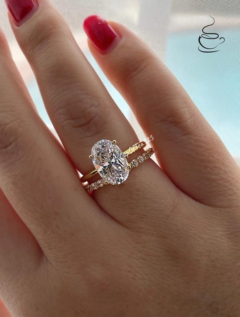 May include: A gold ring with a large oval-shaped clear stone and a smaller band of pave set stones.