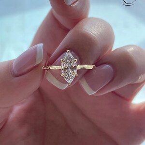 K&ouml;nnte beinhalten: Ein goldener Ring mit einem gro&szlig;en, klaren Marquise-Diamanten.