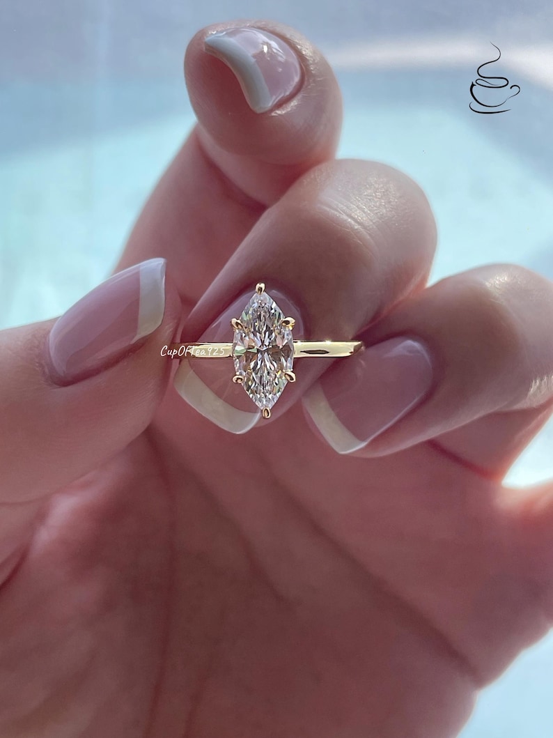 K&ouml;nnte beinhalten: Ein goldener Ring mit einem gro&szlig;en, klaren Marquise-Diamanten.