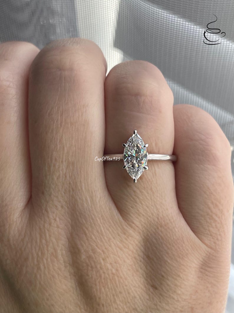 K&ouml;nnte beinhalten: Ein silberner Ring mit einem birnenf&ouml;rmigen Diamanten in einer Krappenfassung.