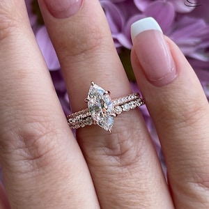 May include: A rose gold engagement ring with a pear-shaped diamond center stone and a matching rose gold band with smaller diamonds.