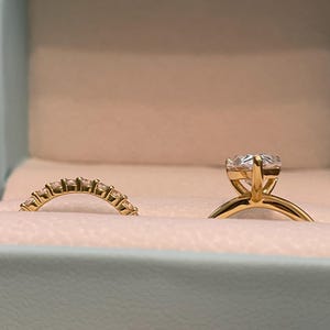 May include: Two gold wedding bands, one with a large round diamond and the other with a row of smaller diamonds.