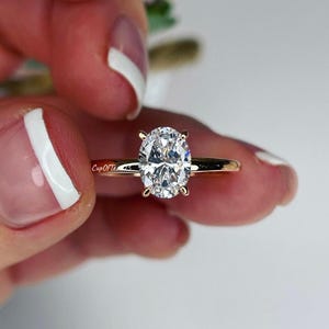 Puede incluir: Un anillo de compromiso de oro rosa con un diamante de forma ovalada.