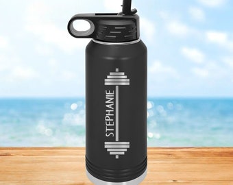 Puede incluir: Botella de agua de acero inoxidable negra con tapa negra y asa de transporte. La botella tiene un diseño de barra de pesas plateada y el nombre "STEPHANIE" grabado en el lateral.