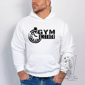 Może przedstawiać: Biała bluza z kapturem z czarnym nadrukiem stopera z tekstem "GYM O'CLOCK".