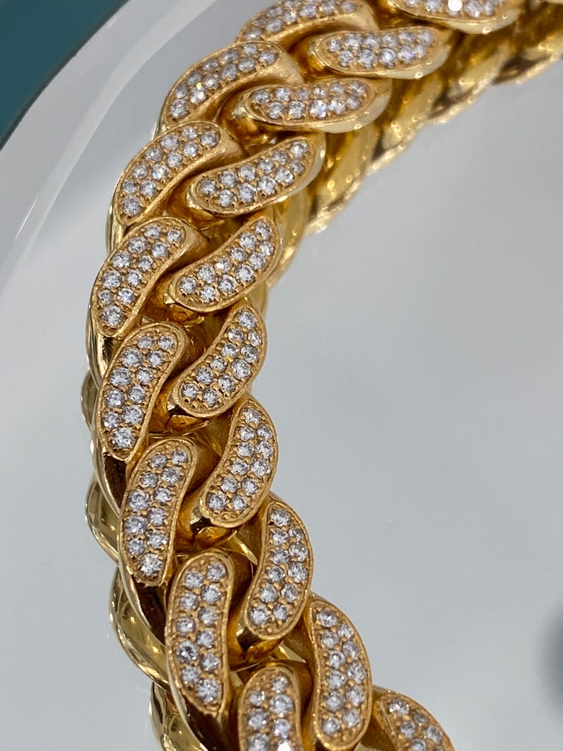 A gold chain with a curb link design. The chain is covered in small, clear, round stones.