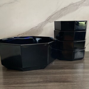 May include: A set of black octagonal glass bowls. The bowls are stacked on top of each other. The bowls are made of thick glass and have a glossy finish.