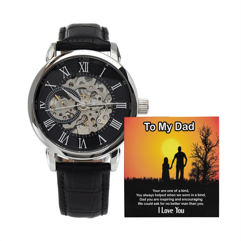 May include: A silver and black skeleton watch with Roman numeral markings on the face, a black leather band, and a small card with the text "To My Dad" and a message about appreciation.