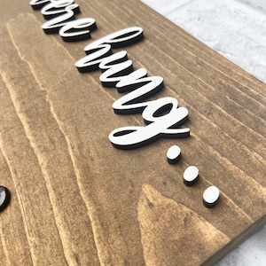 May include: Wooden sign with the phrase "things we love" in white, cursive lettering, and three white dots. The sign is made of stained wood with visible grain.