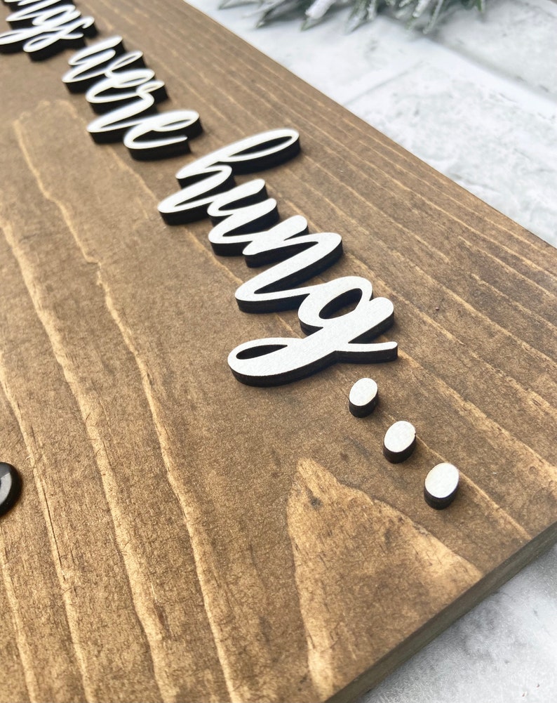 May include: Wooden sign with the phrase "things we love" in white, cursive lettering, and three white dots. The sign is made of stained wood with visible grain.