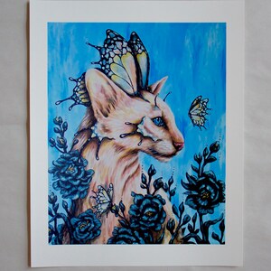 Puede incluir: Un gato blanco con alas de mariposa y ojos azules est&aacute; rodeado de flores azul oscuro y mariposas. El fondo es una acuarela azul claro.