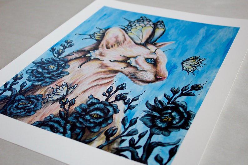 Puede incluir: Un gato blanco con ojos azules y alas de mariposa est&aacute; rodeado de flores azul oscuro sobre un fondo azul claro.